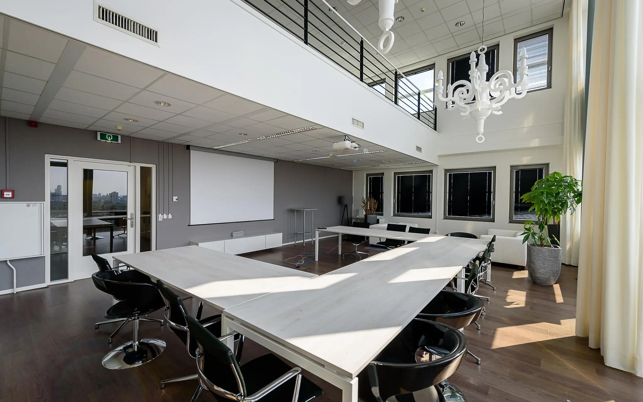 Moderne vergaderruimte in Rivium Boulevard met U-vormige opstelling, grote ramen en een witte kroonluchter.